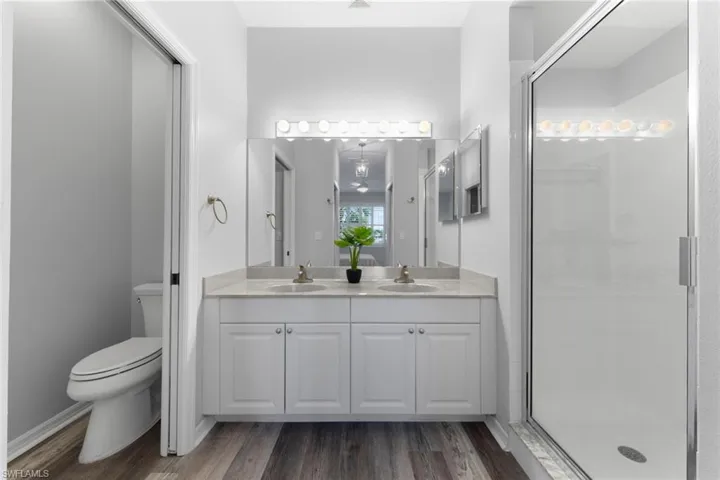 Bathroom featuring vanity, toilet, wood-type flooring, and an enclosed shower