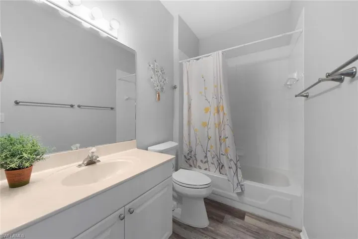 Full bathroom featuring wood-type flooring, toilet, shower / tub combo, and vanity