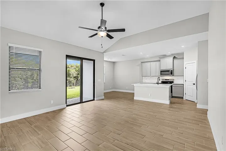 Unfurnished living room featuring wood finish floors, vaulted ceiling, a ceiling fan, and recessed lighting