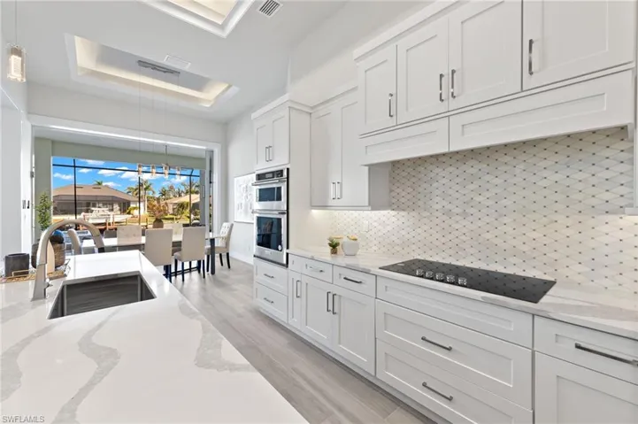 Kitchen featuring backsplash, light stone counters, sink, light hardwood / wood-style flooring, and white cabinetry