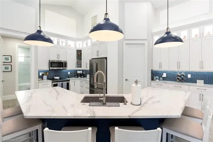 Kitchen featuring a spacious island, pendant lighting, appliances with stainless steel finishes, and tasteful backsplash