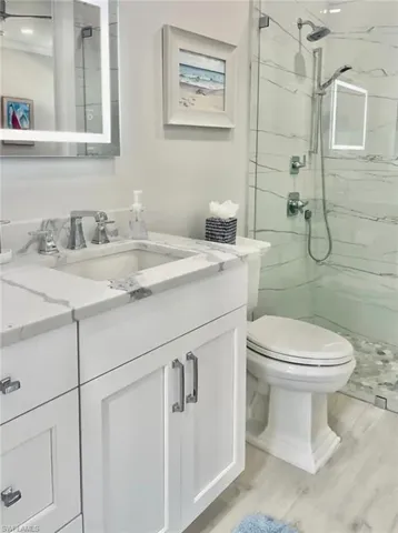 Bathroom with hardwood / wood-style flooring, walk in shower, vanity, and toilet