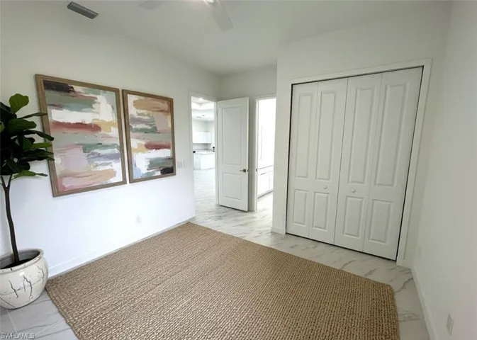 Unfurnished bedroom with light marble finish flooring, a ceiling fan, and a closet