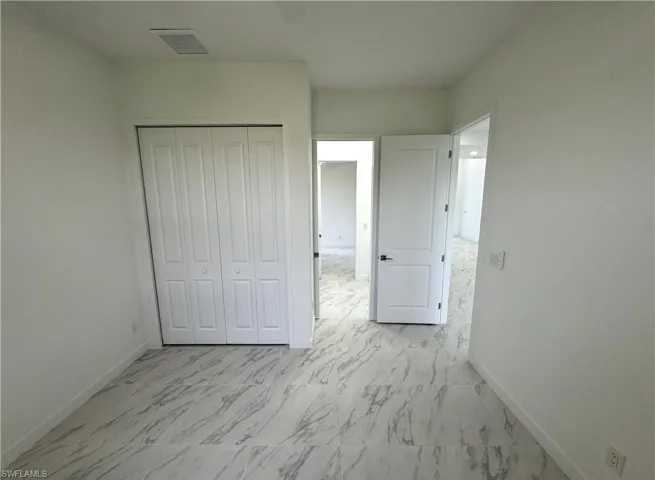 Unfurnished bedroom with light marble finish floors and a closet