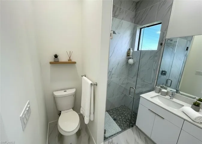 Full bath featuring a marble finish shower, vanity, and light marble finish floors