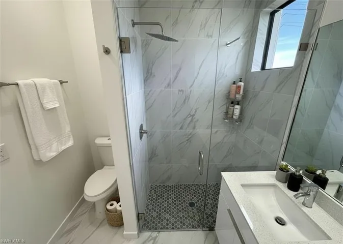 Bathroom featuring vanity, a stall shower, and light marble finish flooring