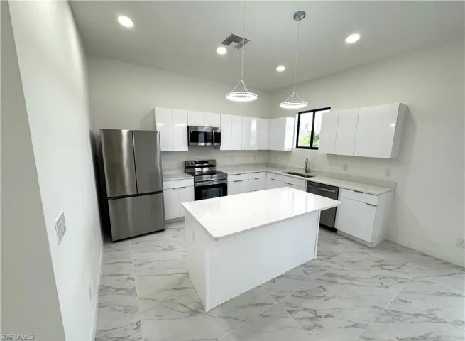 Kitchen with stainless steel appliances, light marble finish flooring, white cabinets, and modern cabinets