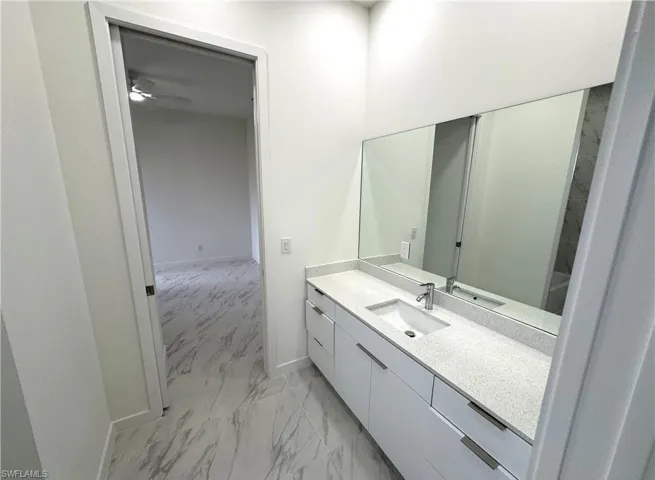 Bathroom featuring light marble finish flooring, vanity, and ceiling fan