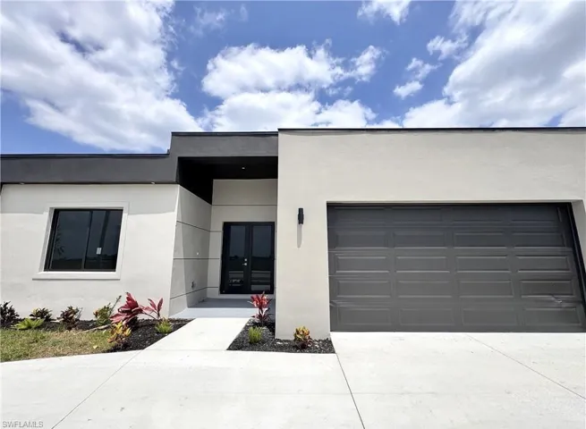 View of front of property with french doors, stucco siding, a garage, and driveway