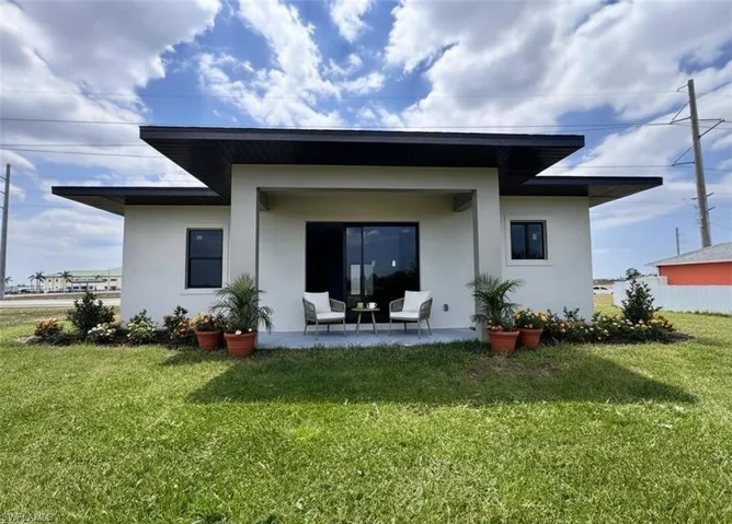 Rear view of property with stucco siding, a patio area, and a lawn