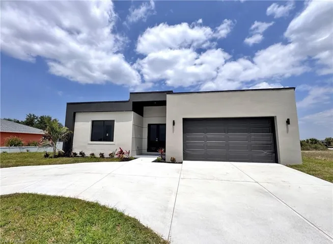 Contemporary house featuring concrete driveway, stucco siding, an attached garage, and a front yard