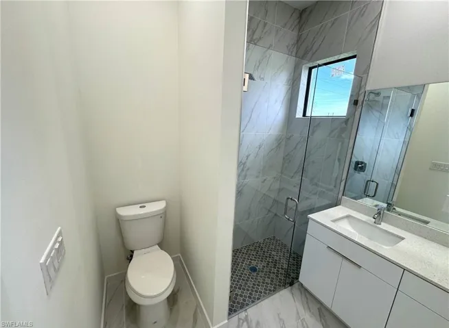 Full bath with a marble finish shower, vanity, and light marble finish floors