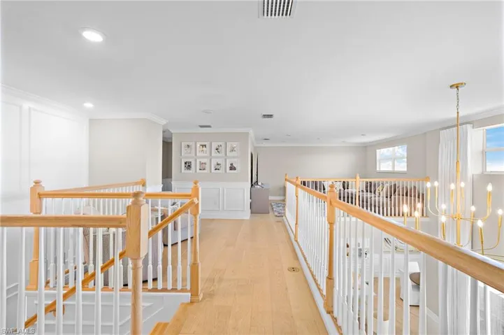 Hall with ornamental molding, a notable chandelier, and light wood-type flooring
