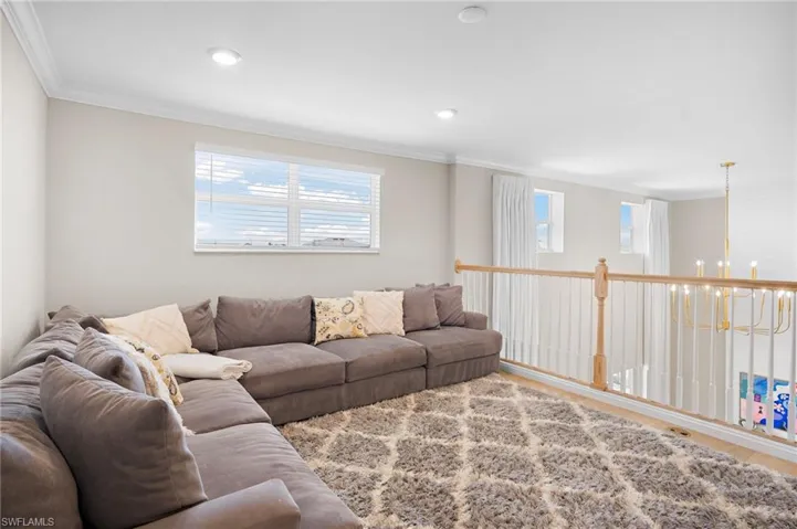 Living room featuring ornamental molding, wood-type flooring, and a chandelier