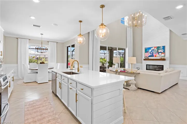 Kitchen with hanging light fixtures, light tile patterned floors, a notable chandelier, sink, and a center island with sink