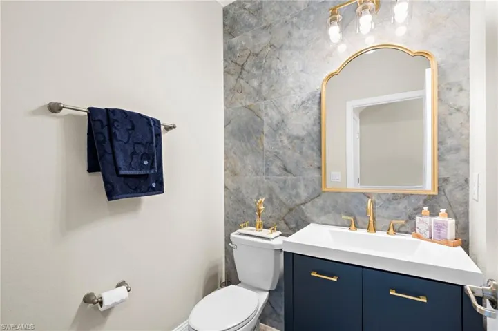 Bathroom featuring vanity, toilet, and tasteful backsplash