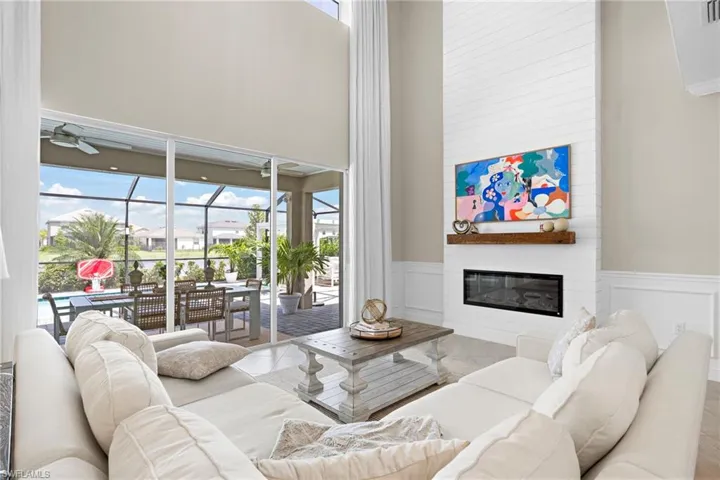Living room with a towering ceiling, ceiling fan, and a large fireplace