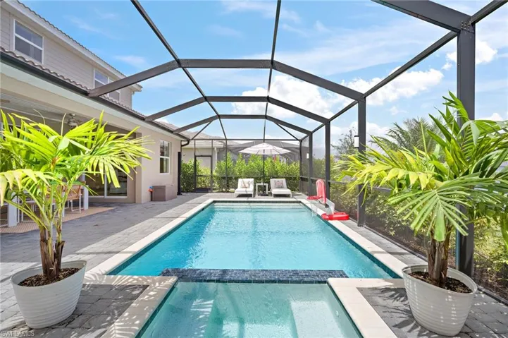 View of pool with glass enclosure and a patio
