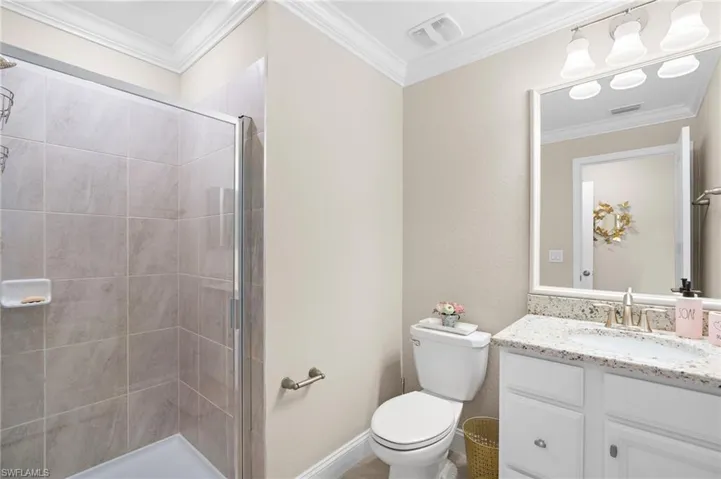 Bathroom featuring vanity, toilet, ornamental molding, and an enclosed shower
