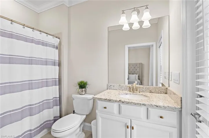 Bathroom with crown molding, vanity, toilet, and a shower with curtain