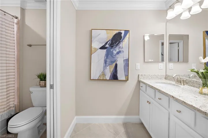 Bathroom featuring vanity, toilet, ornamental molding, a shower with curtain, and tile patterned floors
