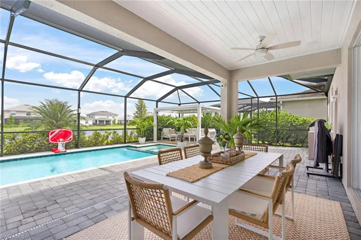 View of pool featuring ceiling fan, a patio area, and glass enclosure
