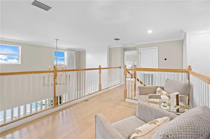 Sitting room with ornamental molding, a notable chandelier, and light hardwood / wood-style floors