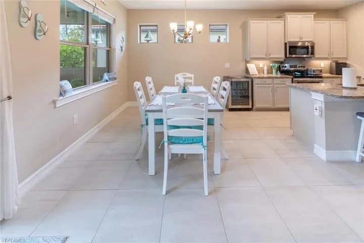 Dining area featuring a notable chandelier, beverage cooler, and light tile floors