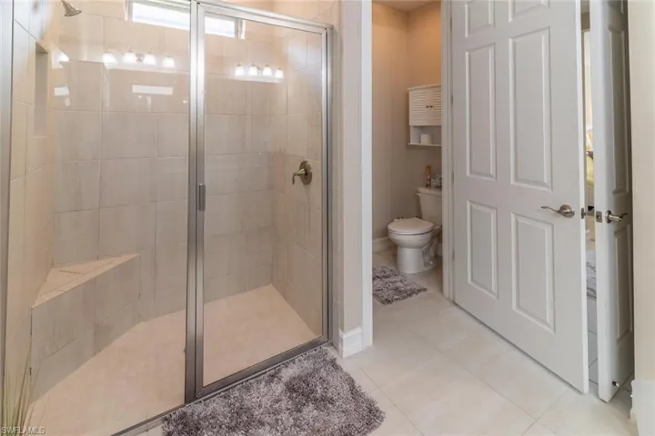 Bathroom with walk in shower, toilet, and tile floors