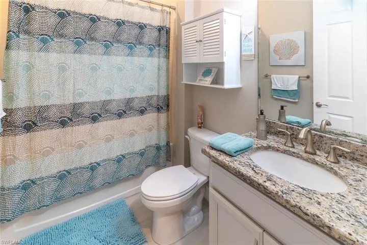 Full bathroom with shower / bath combo, toilet, and large vanity
