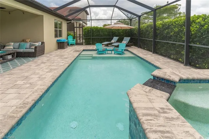 View of swimming pool featuring outdoor lounge area, glass enclosure, pool water feature, and a patio area