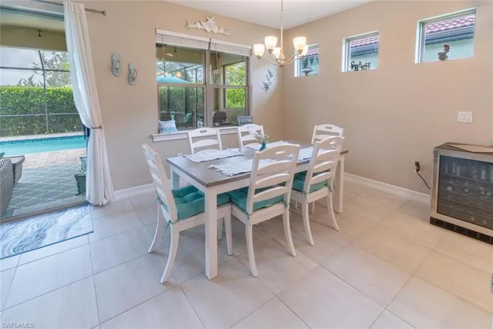 Dining area with a notable chandelier, light tile flooring, and beverage cooler