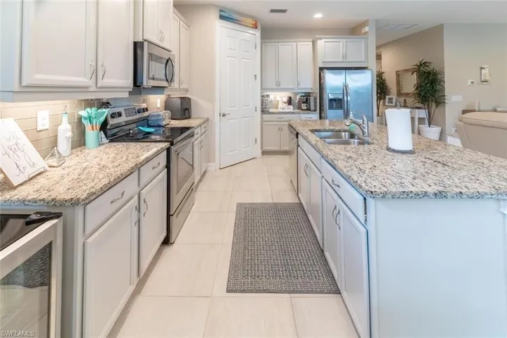 Kitchen with stainless steel appliances, beverage cooler, a center island with sink, and sink