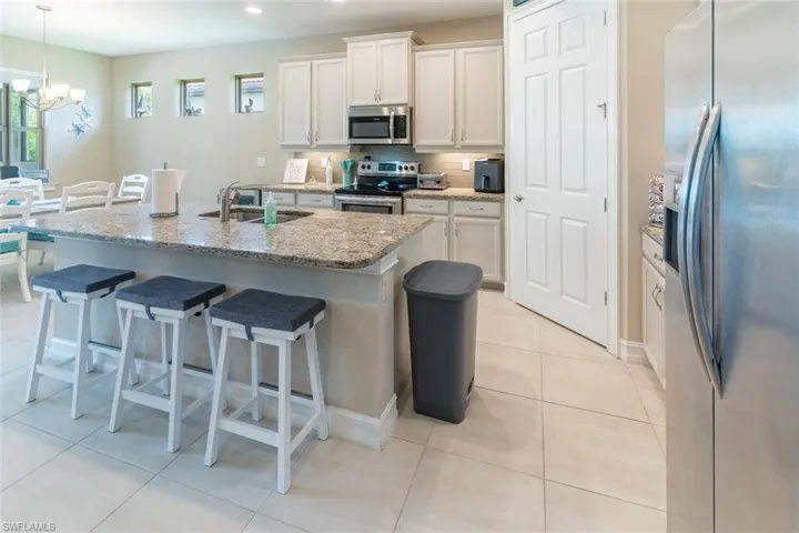 Kitchen featuring decorative light fixtures, an inviting chandelier, stainless steel appliances, white cabinetry, and sink