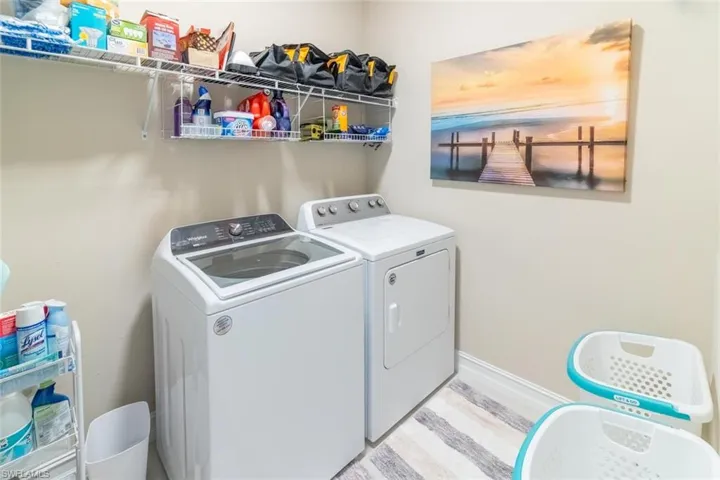 Washroom with light wood-type flooring and washing machine and dryer
