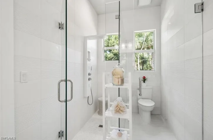 Bathroom featuring a shower stall and tile walls