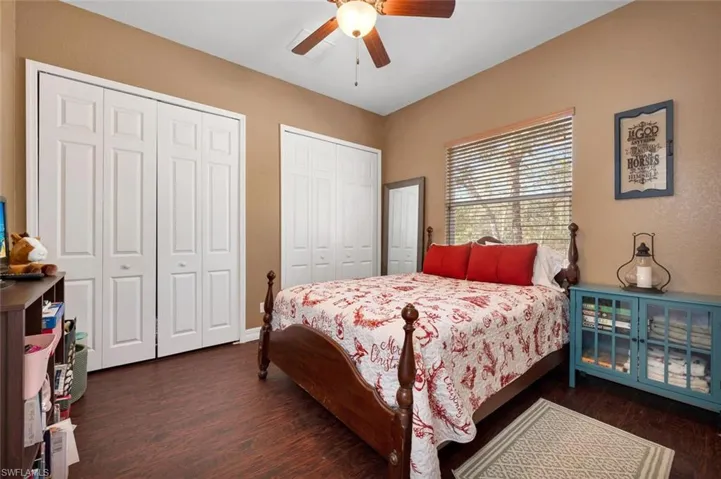 Bedroom with dark hardwood / wood-style flooring, two closets, and ceiling fan