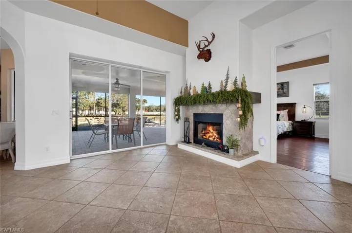 Unfurnished living room featuring a tile fireplace, ceiling fan, and light tile patterned flooring