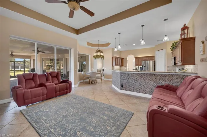 Living room with ceiling fan with notable chandelier and light tile patterned flooring
