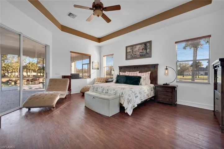Bedroom with ceiling fan, dark hardwood / wood-style flooring, access to outside, and multiple windows
