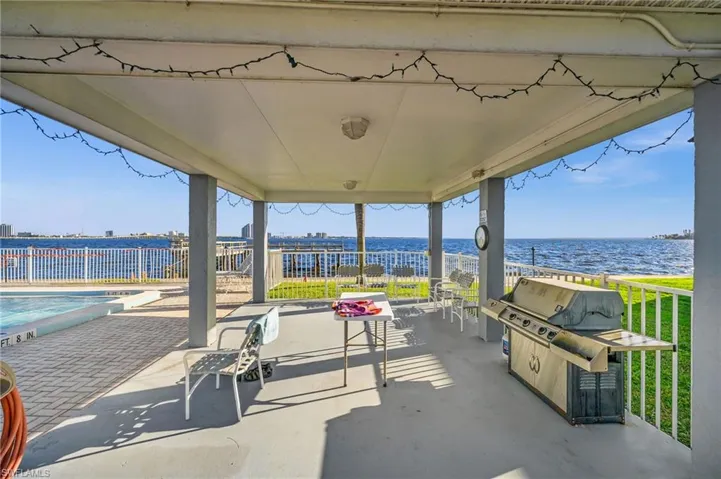 View of patio / terrace with a community pool, a grill, and a water view