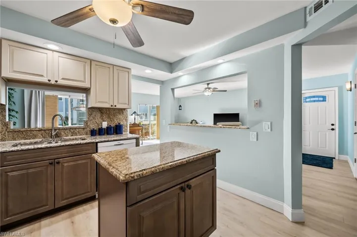 Kitchen featuring light stone counters, a center island, sink, and decorative backsplash