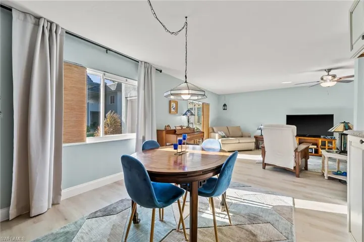 Dining room with vaulted ceiling, ceiling fan, and light wood-type flooring