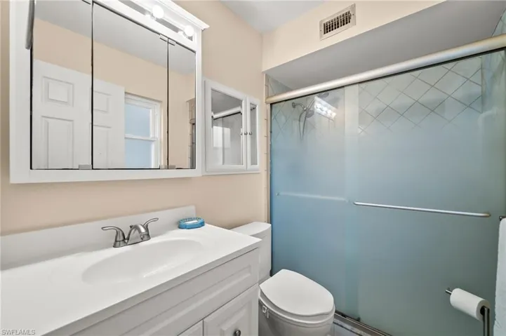 Bathroom with vanity, a shower with door, and toilet