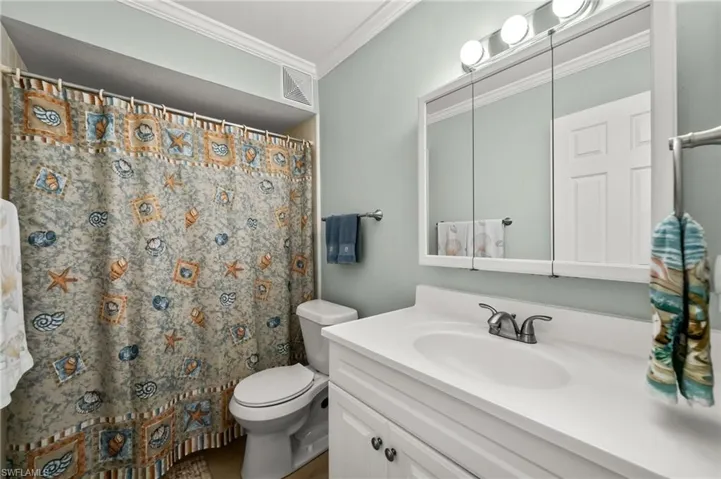 Bathroom featuring crown molding, curtained shower, vanity, and toilet