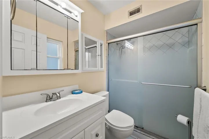 Bathroom with vanity, a shower with shower door, and toilet
