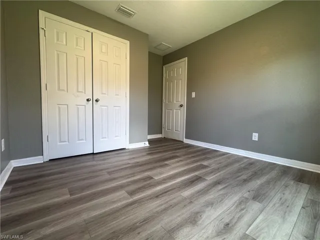 Unfurnished bedroom with dark wood-style flooring and a closet