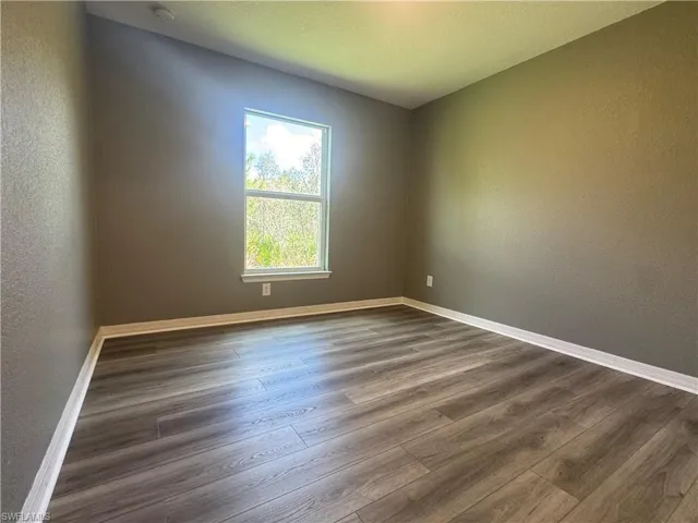 Spare room featuring a textured wall and dark wood-style floors