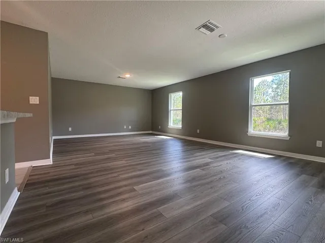 Unfurnished room with dark wood finished floors and a textured ceiling