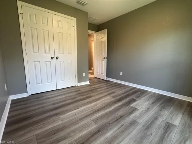 Unfurnished bedroom with a closet and dark wood-style flooring